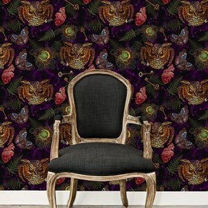 May include: A black upholstered chair with wooden legs sits in front of a dark purple wallpaper with a repeating pattern of owls, butterflies, keys, and roses.