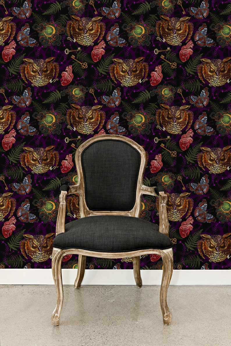 May include: A black upholstered chair with wooden legs sits in front of a dark purple wallpaper with a repeating pattern of owls, butterflies, keys, and roses.