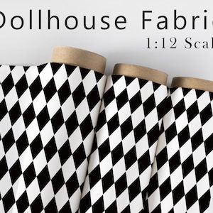 May include: Three rolls of dollhouse fabric with a black and white diamond pattern. The fabric is labeled "Dollhouse Fabric 1:12 Scale". The rolls have a cardboard core and are set against a white background.