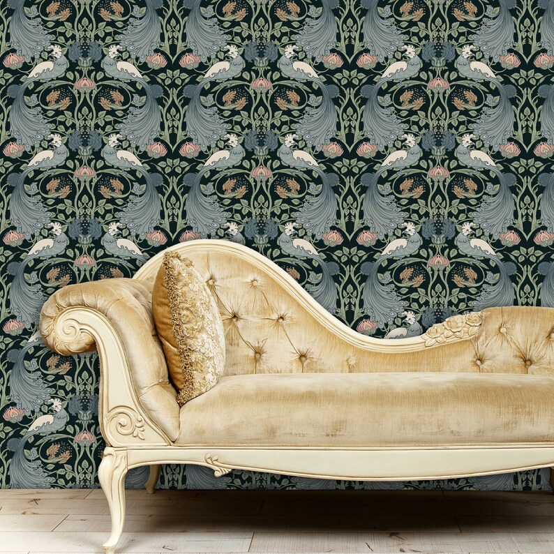 May include: A chaise lounge with a gold fabric upholstery and a white wooden frame. The chaise lounge is in front of a dark blue wallpaper with a repeating pattern of stylized peacocks and flowers.