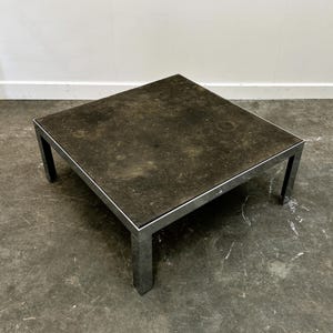 Può includere: Tavolino quadrato con superficie scura e screziata e struttura in metallo argentato. Il tavolo ha un design minimalista ed è adatto per un soggiorno o un'area lounge. Il tavolo misura circa 76 cm di larghezza e 76 cm di lunghezza.