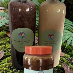 May include: Two tall clear plastic bottles with black caps and one shorter jar with an orange lid. The left bottle contains dark brown Batana Oil shampoo, the right bottle contains beige Batana Oil herbal conditioner, and the jar contains raw Batana Oil.