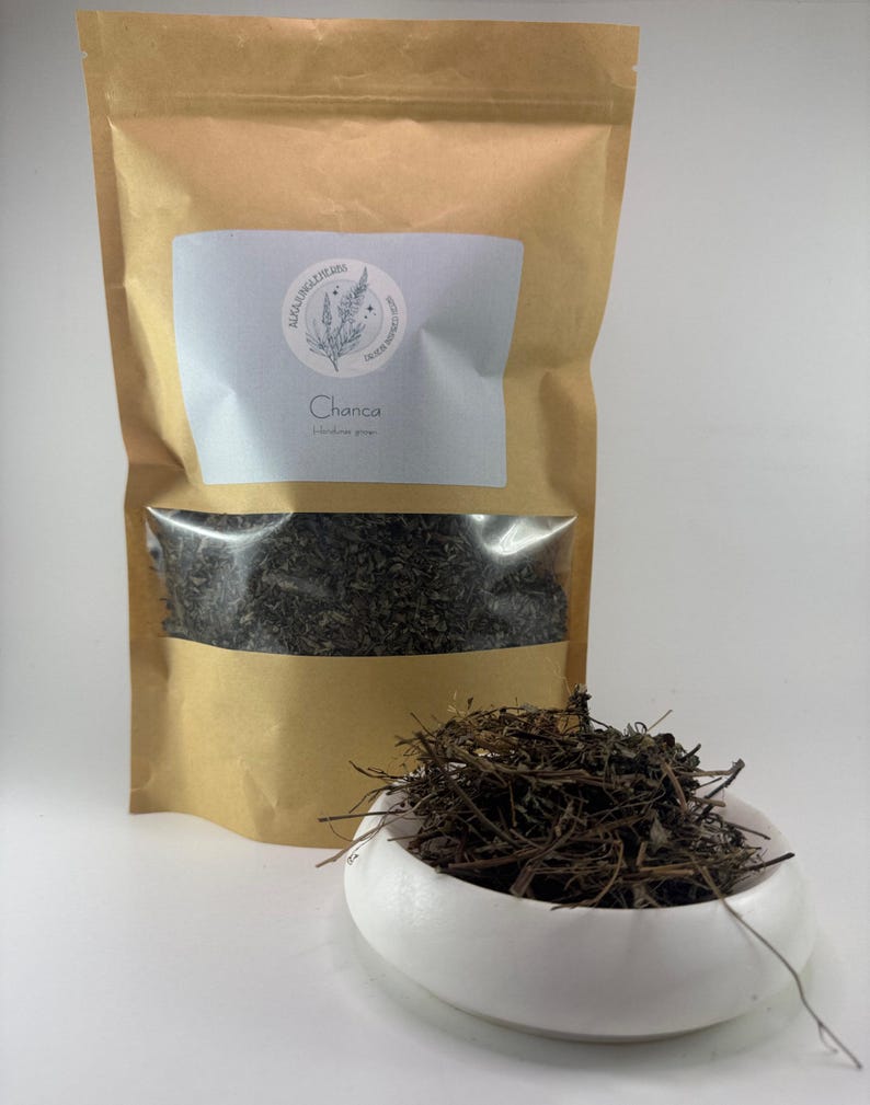 May include: A brown paper bag with a white label that says "Healing Wild Herbs" and "Chanca Piedra" in black text. The bag contains dried herbs. A white bowl with dried herbs in it.