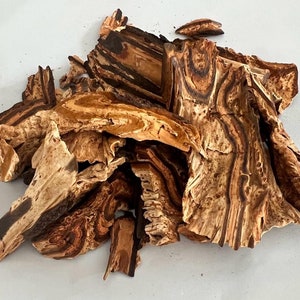 May include: A pile of dried, brown and tan bark with a striped pattern. The bark is broken into irregular pieces.