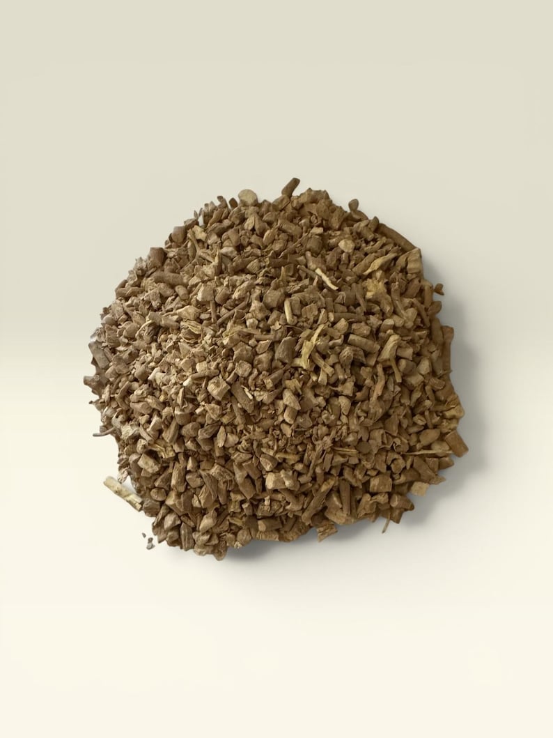 May include: A pile of chopped, dried brown roots, possibly for herbal remedies or culinary use. The pieces vary in size and shape, with a rough, textured appearance. The background is a solid, off-white color, providing contrast to the earthy tones of the roots.