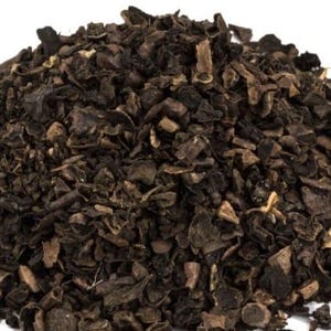 May include: A pile of dark brown, irregularly shaped pieces, possibly dried herbs or spices, against a white background. The pieces have a rough, textured appearance, with some lighter brown and tan tones visible.
