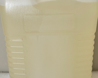 May include: A clear plastic jug with a textured surface. The jug is filled with a light yellow liquid.