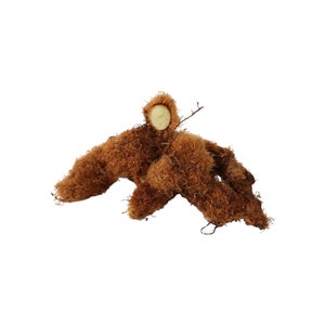 May include: A brown, fibrous root with a light brown, partially exposed center. The root is shaped like a human figure with arms outstretched.