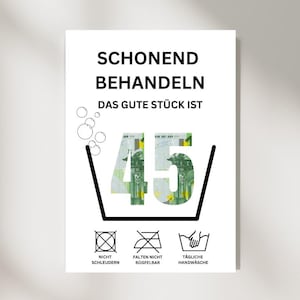 Könnte beinhalten: Ein weißes Schild mit schwarzem Text, der "Schonend Behandeln Das Gute Stück Ist 45/" lautet, mit einem Bild eines 45-Euro-Scheins in einem Waschmaschinensymbol. Unter dem Symbol befinden sich drei weitere Symbole: ein Kreis mit einem Kreuz, ein Kreis mit einem Kreuz und einer diagonalen Linie und ein Handwaschsymbol. Der Text unter den Symbolen lautet "Nicht Schleudern", "Falten Nicht Bügelbar" und "Tägliche Handwäsche".