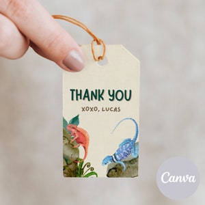 Può includere: Un'etichetta di ringraziamento beige con testo verde che dice "THANK YOU" e "XOXO, LUCAS". L'etichetta presenta un'illustrazione ad acquerello di un camaleonte rosso e una lucertola blu su uno sfondo verde frondoso.