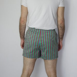 May include: A pair of checkered shorts with a green, blue, and red pattern. The shorts are made of a lightweight fabric and have a comfortable fit.