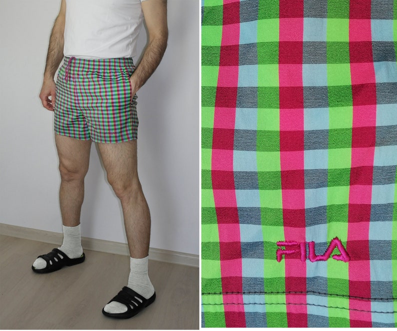 May include: Green, pink, and blue checkered swim trunks with the word "FILA" embroidered in pink on the left leg.