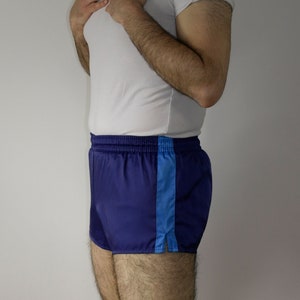 Op de afbeelding: Blauwe sport shorts met een blauwe streep aan de zijkant. De shorts hebben een elastische tailleband en een trekkoord.