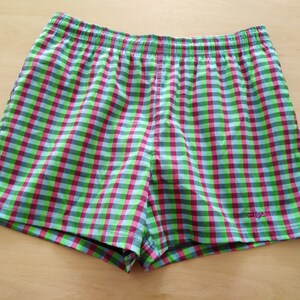 May include: Green, pink, and blue checkered swim trunks with a white "FILA" logo on the right side.