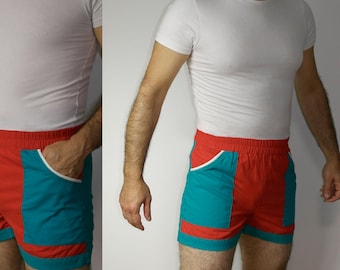 Può includere: Pantaloncini sportivi rossi e blu-verde con cintura bianca e bordatura bianca. I pantaloncini hanno una tasca su ogni lato.