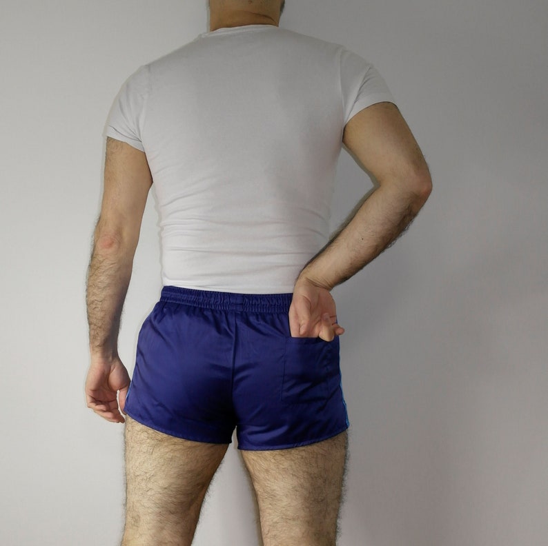 Op de afbeelding: Een persoon draagt een wit T-shirt en blauwe sport shorts met witte bies.