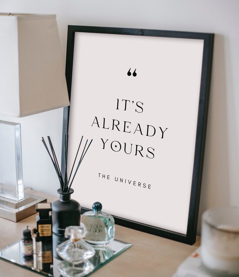 May include: A black framed print with a white background and the text "It's already yours - The Universe" in black font.