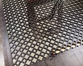 May include: A dark brown wooden table with a decorative, openwork top featuring a repeating quatrefoil pattern. The table's edges have a darker, wood-grain finish. The table is likely for indoor use.