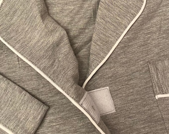 May include: Gray long-sleeved shirt with white piping around the collar, cuffs, and pockets. The shirt has a small label with the text "Walter & Co. The Sleepwear" and the size "M".