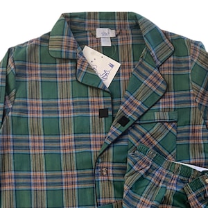 May include: Green and orange plaid pajama set with a button-up top and matching pants. The top has a collar and a pocket on the left chest. The pants have an elastic waistband.