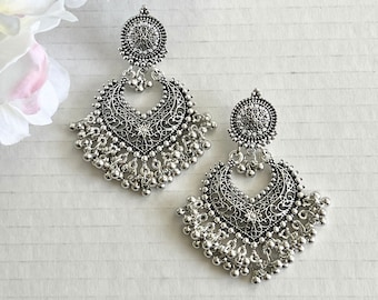 May include: A pair of silver dangle earrings with intricate filigree designs and dangling beads. The earrings have a circular top with a floral design.