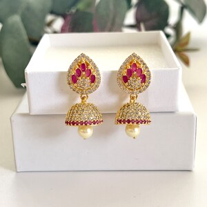 以下が含まれることがあります： ピンクの石と真珠のアクセントが付いた涙の滴のデザインの金のイヤリング
