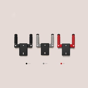 May include: Three motorcycle footrest assemblies, each featuring a black mounting bracket and two cylindrical pegs. The pegs are available in black, gray, or red, each with a textured, knurled surface. Below each assembly is a colored dot and text.