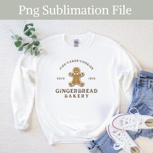May include: White sweatshirt with a brown gingerbread man graphic and the text "Pies Cakes Cookies Est. 1903 Gingerbread Bakery".