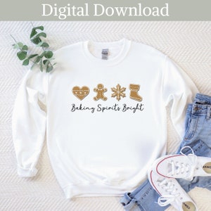 May include: White sweatshirt with a gingerbread cookie design and the text "Baking Spirits Bright".