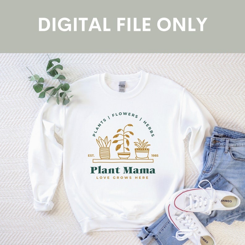 Puede incluir: Sudadera blanca con un gr&aacute;fico dorado de plantas en maceta y el texto "PLANTS | FLOWERS | HERBS", "EST. 1985", "Plant Mama" y "LOVE GROWS HERE".