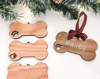 May include: Three wooden dog bone ornaments with a paw print cutout. One ornament is personalised with the name "Bailey".