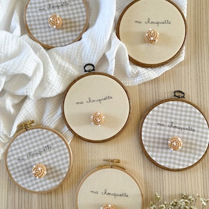 Pode incluir: Seis aros de bordado com o texto "ma chouquette" e um design de pastelaria de crochê no centro. Os aros estão sobre uma superfície de madeira com um pano branco no fundo.