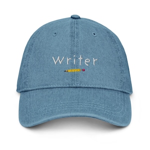 May include: A blue denim baseball cap with the word "Writer" embroidered in white and a yellow pencil with a red eraser embroidered below it.