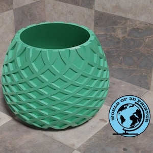 May include: A teal green planter with a geometric pattern. The planter is round and has a wide opening at the top.