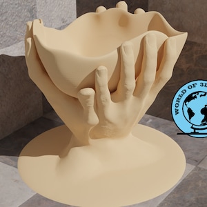 May include: A beige ceramic sculpture of two hands holding a bowl. The sculpture is on a beige base and is sitting on a tiled surface.