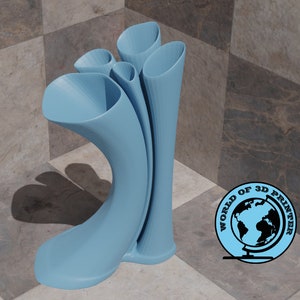 Puede incluir: Un jarrón de color azul claro impreso en 3D con un diseño curvo único. El jarrón tiene cuatro aberturas, cada una con un tamaño y una forma diferentes. El jarrón está sentado en un suelo de baldosas de ajedrez.