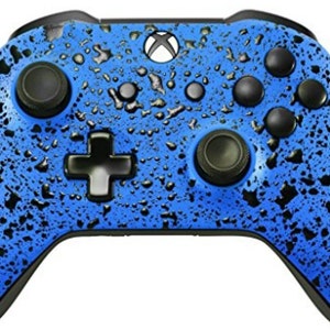 May include: A blue Xbox controller with a black splatter paint design. The controller has a textured surface that resembles raindrops.
