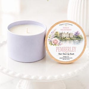 May include: A light purple candle in a round container with a wooden lid. The lid features a label with a watercolor illustration of a manor, a swan, and flowers, with the text Pemberley, Hand-Poured Soy Candle, and Net wt. 3.5 oz.