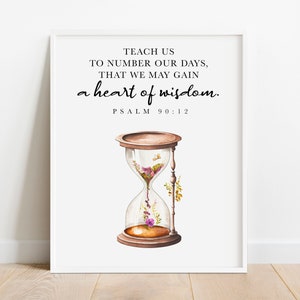 May include: Framed art print featuring an hourglass filled with flowers and the text "TEACH US TO NUMBER OUR DAYS, THAT WE MAY GAIN a heart of wisdom. PSALM 90:12". The hourglass has a brown wooden frame and base.