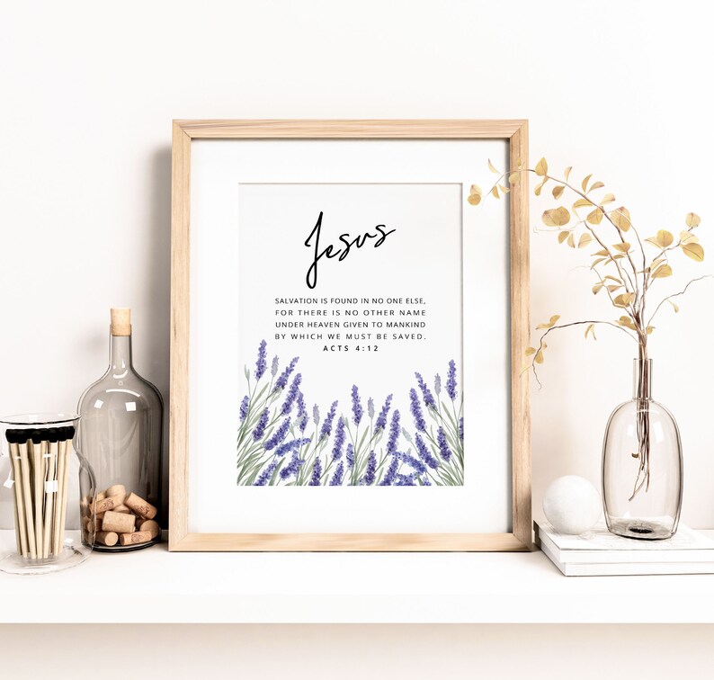 K&ouml;nnte beinhalten: Gerahmter Druck mit dem Wort "Jesus" in eleganter Schrift. Der Druck enth&auml;lt einen Bibelvers und Lavendel-Illustrationen. Der Rahmen ist aus hellem Holz, und die Gesamt&auml;sthetik ist minimalistisch und heiter.