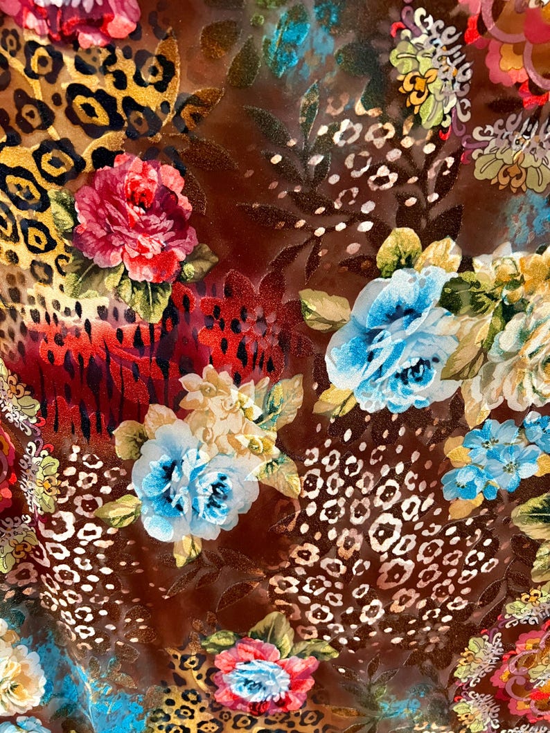 May include: A brown fabric with a colorful floral pattern. The fabric features a mix of red, blue, yellow, and white flowers, as well as a leopard print pattern.