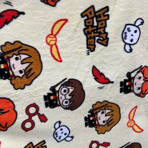 May include: A cream-colored fabric with a repeating pattern of Harry Potter characters, including Harry, Ron, Hermione, and Hedwig the owl. The fabric also features the words "Harry Potter" and the Golden Snitch.