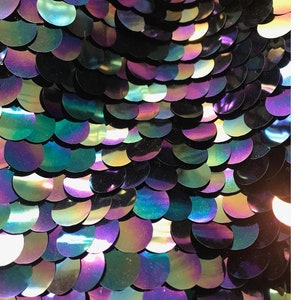 May include: Close-up of iridescent sequins in shades of purple, green, and blue arranged in a scale-like pattern.