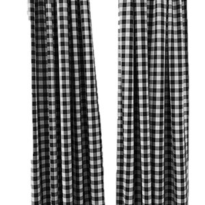 May include: Two black and white checkered curtains hanging from a rod. The curtains are made of a soft, woven fabric and have a classic gingham pattern.