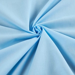 May include: A close-up of a light blue fabric, folded and twisted into a spiral shape. The fabric is smooth and has a subtle sheen.
