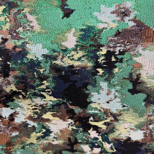 May include: Abstract fabric with a green, brown, black, and white camouflage pattern. The fabric has a textured, woven look.