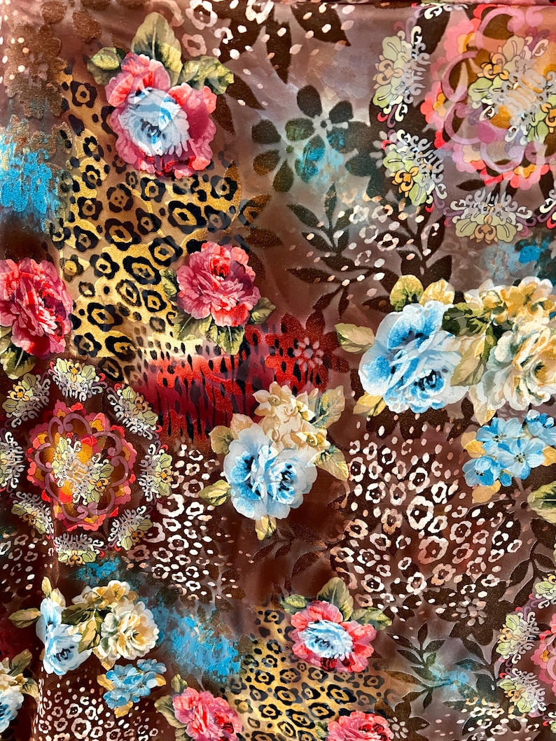 May include: A brown fabric with a floral and leopard print pattern. The flowers are in shades of pink, red, blue, and yellow. The leopard print is in shades of brown and black.