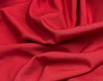 Peut inclure: Gros plan sur un tissu rouge lisse avec une texture subtile. Le tissu est drapé et plié, créant des courbes et des plis doux.