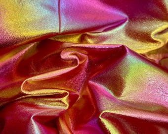 Puede incluir: Primer plano de una tela iridiscente con un esquema de color rosa, dorado y verde. La tela está doblada y drapeada, creando una textura suave y fluida.