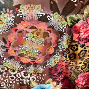 May include: A brown sheer fabric with a colorful floral pattern. The fabric features a variety of flowers, including roses, daisies, and other floral designs. The fabric also has a leopard print pattern.